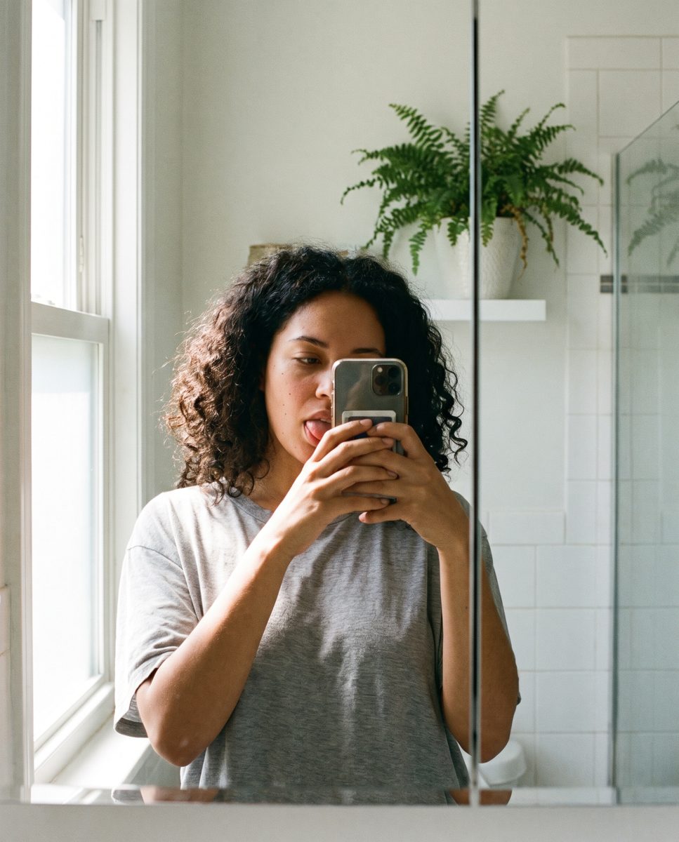 A woman looks at her tongue in the mirror
